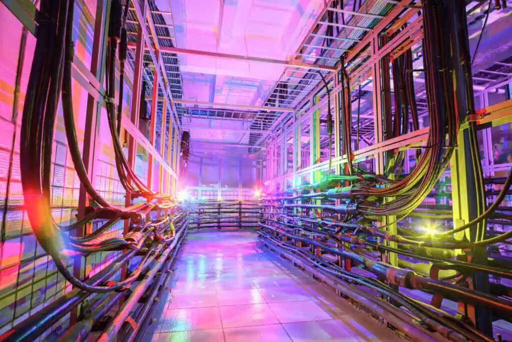 The technical room with many cables is illuminated by multi-colored lights.