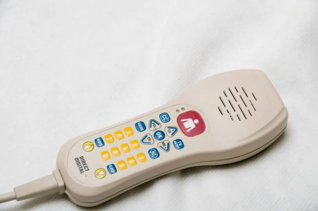 A TV remote control with a nurse call button.